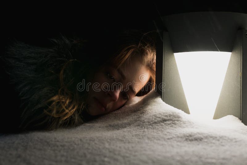 Ung flicka som leker i snö på natten. En ung flicka spelar i snö på natten nära ett lanternt