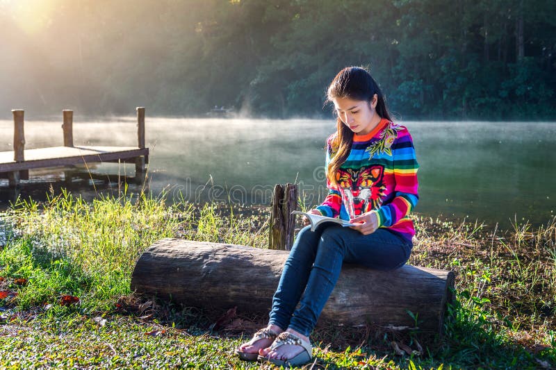 Ung flicka som läser en bok i parkera arkivfoto Ung flicka som läser en bok i parkera arkivfoto