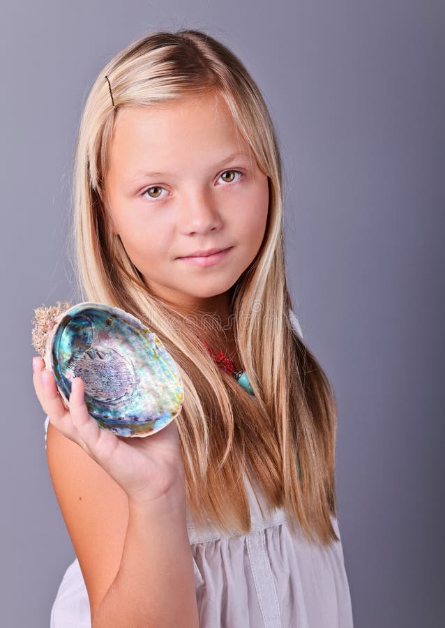 Ung flicka som rymmer ett snäckskal royaltyfri fotografi Ung flicka som rymmer ett snäckskal royaltyfri fotografi