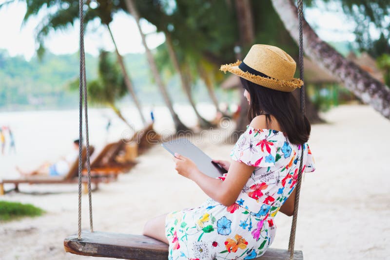 Ung flicka som sitter på stranden med digital tablett