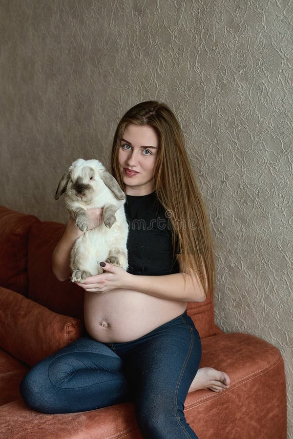 Ung gravid kvinna Gravid h?rlig kvinna med kanin som hemma poserar lyckligt havandeskap arkivbilder Ung gravid kvinna Gravid h?rlig kvinna med kanin som hemma poserar lyckligt havandeskap arkivbilder