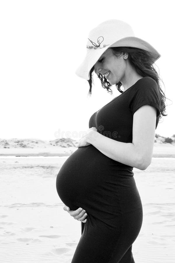 Ung gravid kvinna i en svart klänning arkivbild Ung gravid kvinna i en svart klänning arkivbild