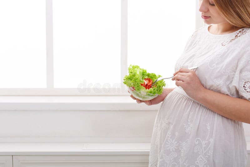 Ung gravid kvinna som äter ny grön sallad royaltyfria foton Ung gravid kvinna som äter ny grön sallad royaltyfria foton