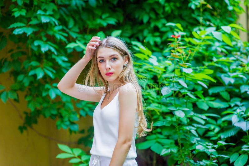 Ung h?rlig flicka som poserar den utomhus- b?rande trendiga vita kl?nningen Sommarstil arkivbild Ung h?rlig flicka som poserar den utomhus- b?rande trendiga vita kl?nningen Sommarstil arkivbild