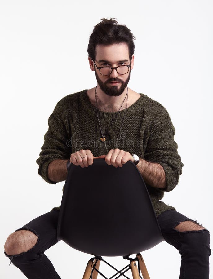 Ung hipster på stol i studio royaltyfria bilder Ung hipster på stol i studio royaltyfria bilder
