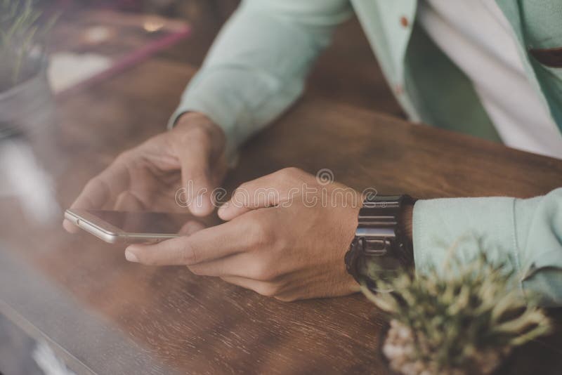 Ung hipstergrabb som smsar med hans mobiltelefon på stången royaltyfri foto Ung hipstergrabb som smsar med hans mobiltelefon på stången royaltyfri foto