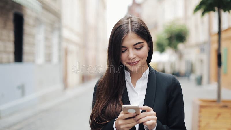 Ung härlig affärskvinna som använder smartphonen och går på den gamla gatan Henne som surfar internet Begrepp: nytt