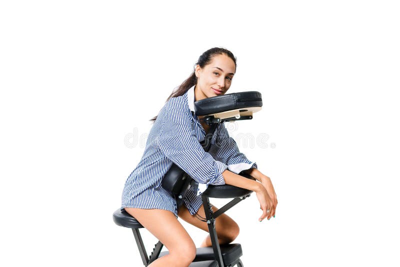 Ung härlig arbetare för flickabrunettkontor i en skjorta och med kala ben som sitter på en massagestol Mörkt hud och hår av en br royaltyfri foto Ung härlig arbetare för flickabrunettkontor i en skjorta och med kala ben som sitter på en massagestol Mörkt hud och hår av en br royaltyfri foto