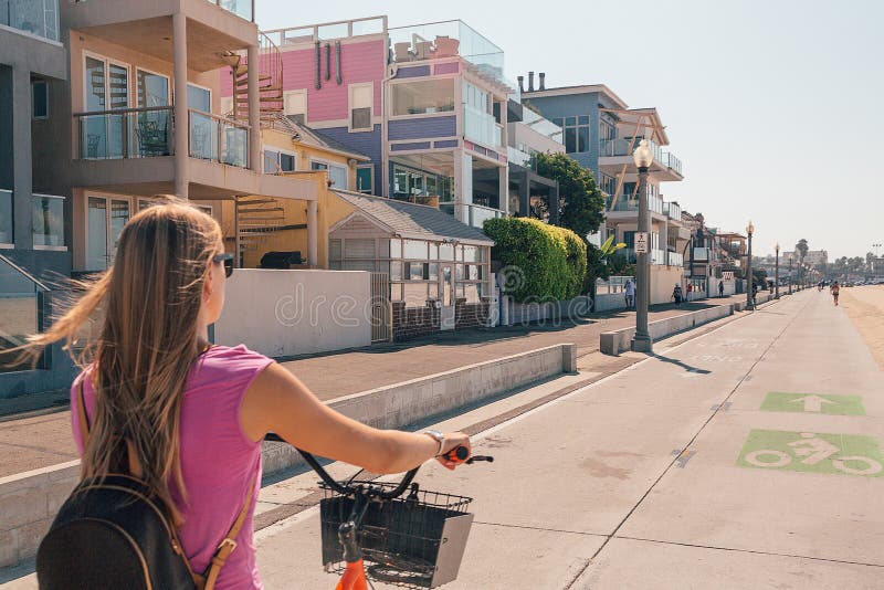 Ung härlig flicka som rider en cykel ner den Venedig stranden arkivfoto Ung härlig flicka som rider en cykel ner den Venedig stranden arkivfoto