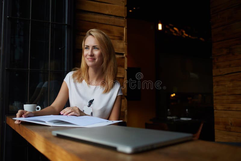 Ung härlig hipsterflicka med bra lynnesammanträde med den stora notepaden i coffee shop under hennes rekreationtid, arkivfoton Ung härlig hipsterflicka med bra lynnesammanträde med den stora notepaden i coffee shop under hennes rekreationtid, arkivfoton