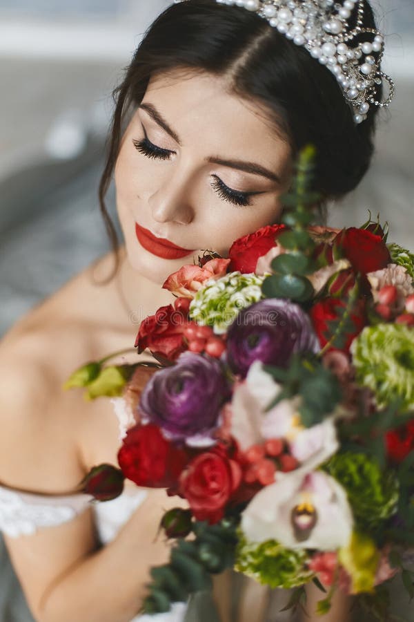 Ung härlig och sexig brunettkvinna, i den vita klänningen och diademen på hennes huvud, med blommor i hennes händer fotografering för bildbyråer Ung härlig och sexig brunettkvinna, i den vita klänningen och diademen på hennes huvud, med blommor i hennes händer fotografering för bildbyråer