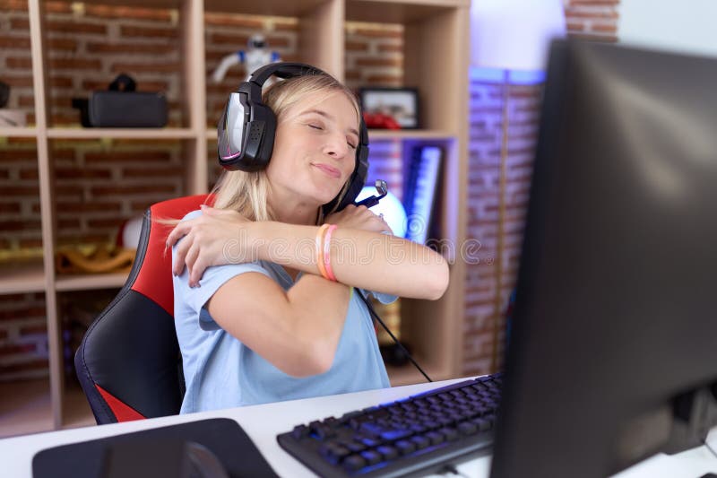 Ung kaukasisk kvinna som spelar videospel med hörlurar som kramar sig själv, glad och positiv, leende självsäker royaltyfri bild