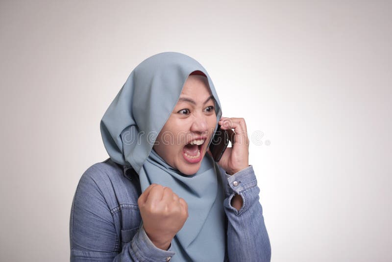 Young Asian muslim woman angry by phone call, screaming on her phone. Close up body portrait isolated on white. Young Asian muslim woman angry by phone call, screaming on her phone. Close up body portrait isolated on white