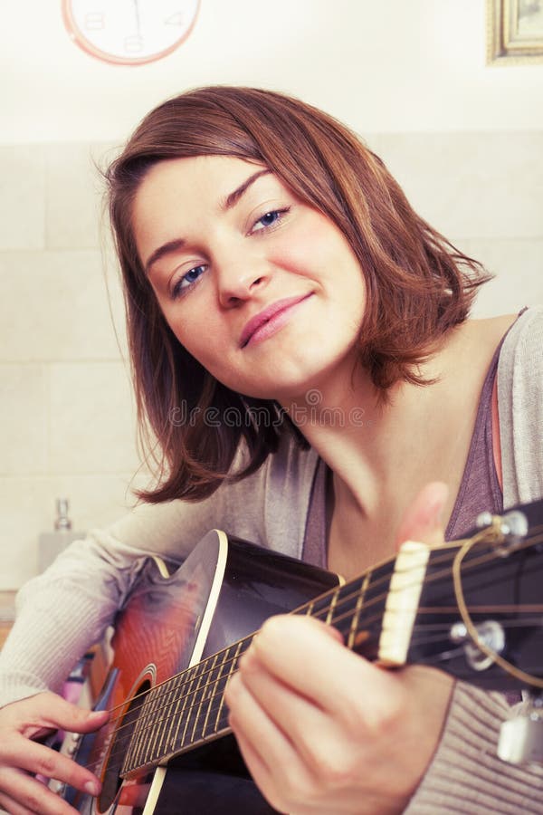Ung kvinna för härlig brunett med en gitarr royaltyfria bilder Ung kvinna för härlig brunett med en gitarr royaltyfria bilder