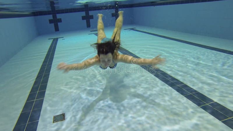 Ung kvinna i blå bikini simmar under vatten i stock video