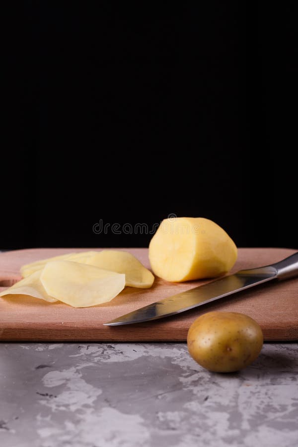 Ung kvinna i en apron skär potatis royaltyfri fotografi