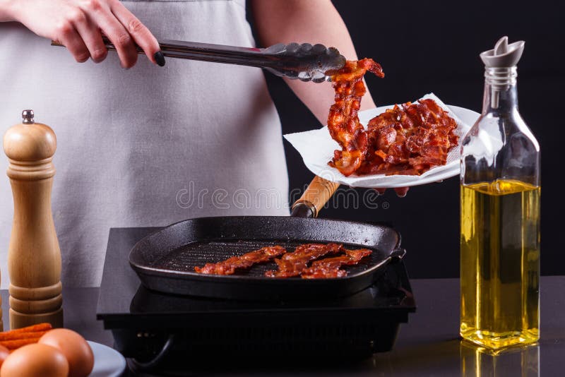 Ung kvinna i en grå aprons bacon arkivbild