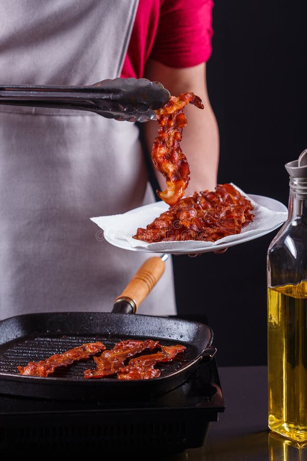 Ung kvinna i en grå aprons bacon arkivfoto