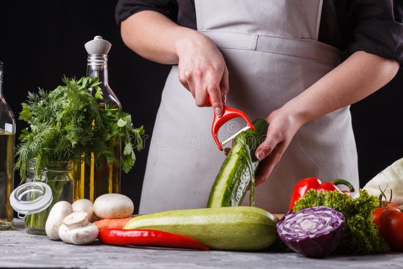 Ung kvinna i grått aprons gurka arkivfoto