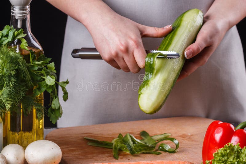 Ung kvinna i grått aprons gurka royaltyfri bild