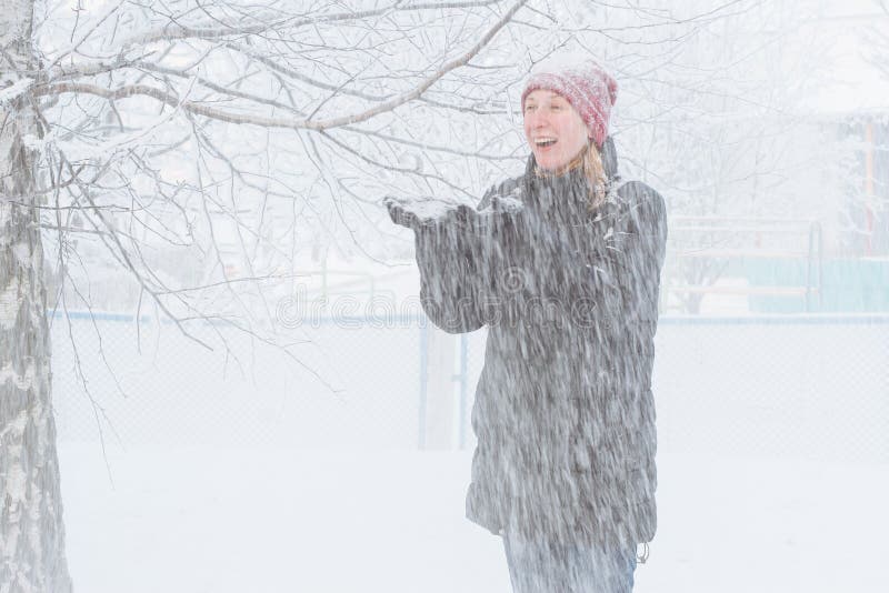 Ung kvinna i staden i snön. Tungt snöfall i staden och ett anseende för ung kvinna under den fallande snön