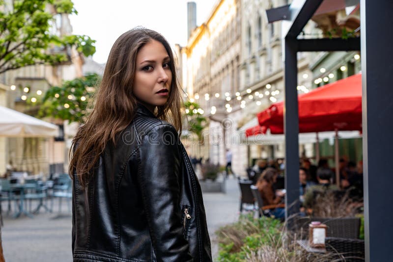 Ung kvinna i svart en vänd för ställning för läderomslag halva på gatan av den Lviv staden Gatamodefotografi med den härliga kvin arkivfoto Ung kvinna i svart en vänd för ställning för läderomslag halva på gatan av den Lviv staden Gatamodefotografi med den härliga kvin arkivfoto