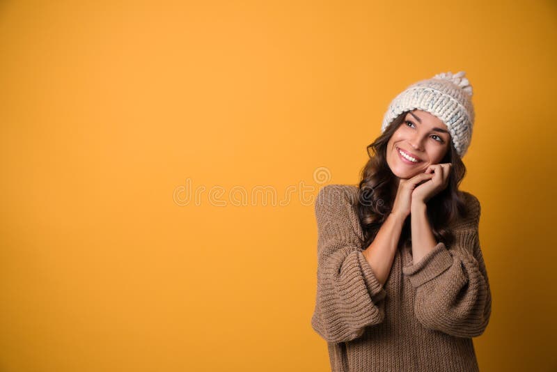 Ung kvinna i varm tröja och hatt på gul bakgrund Juls?song royaltyfri fotografi Ung kvinna i varm tröja och hatt på gul bakgrund Juls?song royaltyfri fotografi