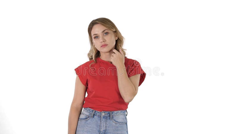 Ung kvinna med blont h?r i den r?da T-tr?ja som ser kameran som ?r k?nslol?s p? vit bakgrund fotografering för bildbyråer Ung kvinna med blont h?r i den r?da T-tr?ja som ser kameran som ?r k?nslol?s p? vit bakgrund fotografering för bildbyråer