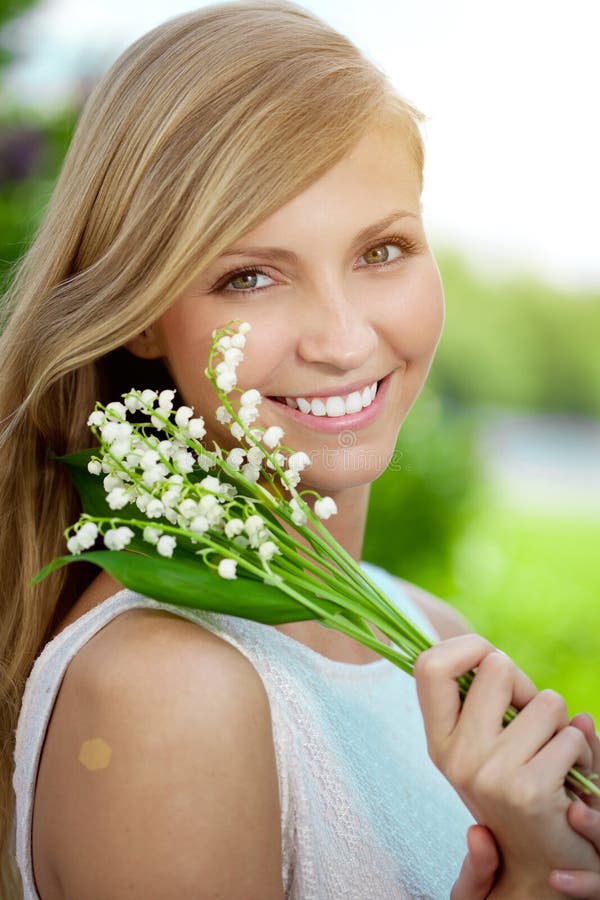 Ung kvinna med ett härligt leende med sunda tänder med flowe royaltyfri bild Ung kvinna med ett härligt leende med sunda tänder med flowe royaltyfri bild