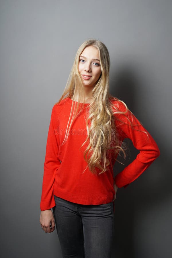 Ung kvinna med långt anseende för blont hår mot den gråa väggen royaltyfri foto Ung kvinna med långt anseende för blont hår mot den gråa väggen royaltyfri foto