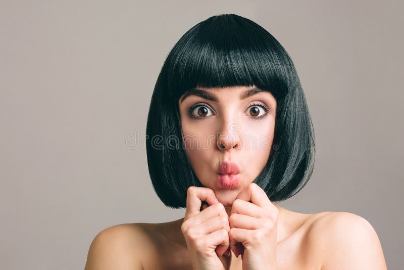 Ung kvinna med svart h?r som poserar p? kamera Den förbluffade emotionella modellen med guppar frisyr Rymma stycken av hår mellan arkivbilder Ung kvinna med svart h?r som poserar p? kamera Den förbluffade emotionella modellen med guppar frisyr Rymma stycken av hår mellan arkivbilder