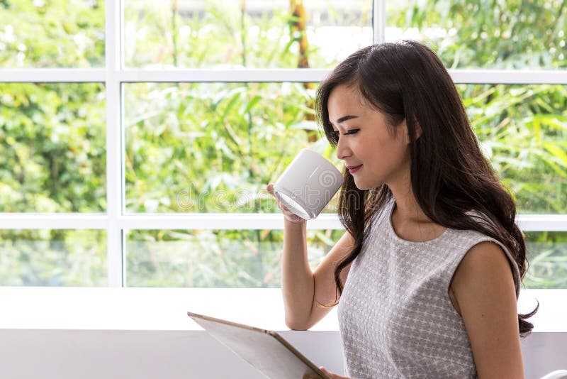 Ung kvinna som använder minnestavlan i coffee shop Kvinnabruksmobiltelefon på coffee shop arkivbilder Ung kvinna som använder minnestavlan i coffee shop Kvinnabruksmobiltelefon på coffee shop arkivbilder