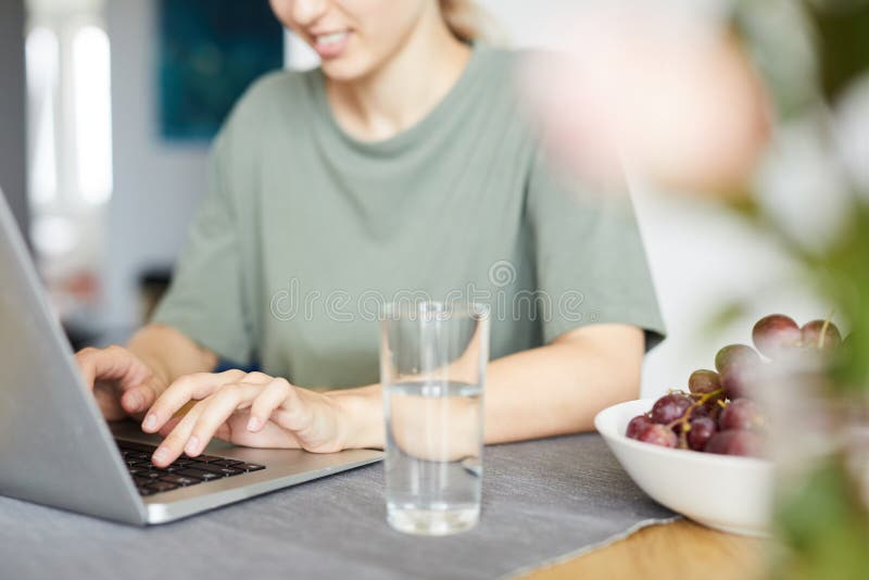 Ung kvinna som framme sitter av bärbara datorn vid köksbordet hemma fotografering för bildbyråer Ung kvinna som framme sitter av bärbara datorn vid köksbordet hemma fotografering för bildbyråer