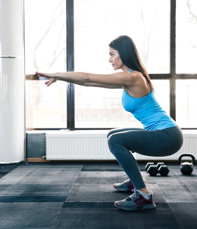 Ung kvinna som gör squats arkivfoton