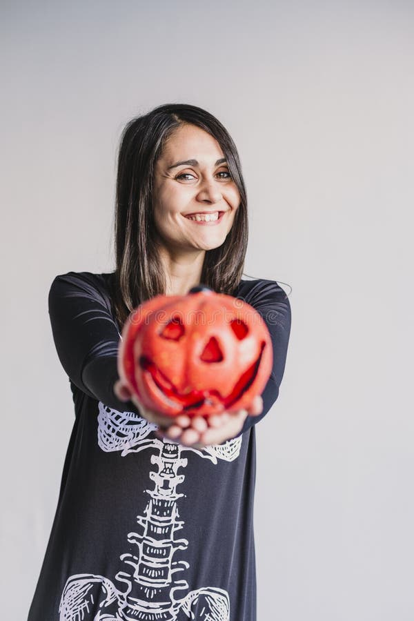 Ung kvinna som hÃ¥ller pumpa och leker. Med ett svart och vitt skelett. f? r den grymma s? ger miniatyrreaperen halloween f? r kalend royaltyfri fotografi