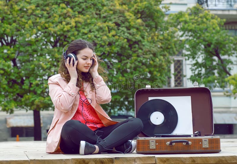 Ung kvinna som lyssnar till musik i en parkera Stående av flickan som känner sig som är bra med sånger på gammalt stereo- vinylsy arkivfoto Ung kvinna som lyssnar till musik i en parkera Stående av flickan som känner sig som är bra med sånger på gammalt stereo- vinylsy arkivfoto