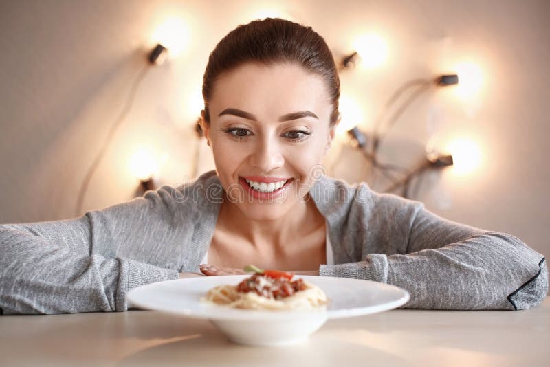 Ung kvinna som ser plattan med smaklig pasta på tabellen arkivfoto Ung kvinna som ser plattan med smaklig pasta på tabellen arkivfoto