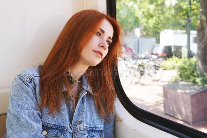Ung kvinna som sitter i sp?rvagnen eller sp?rvagnen som ser ut ur f?nstret royaltyfri fotografi Ung kvinna som sitter i sp?rvagnen eller sp?rvagnen som ser ut ur f?nstret royaltyfri fotografi