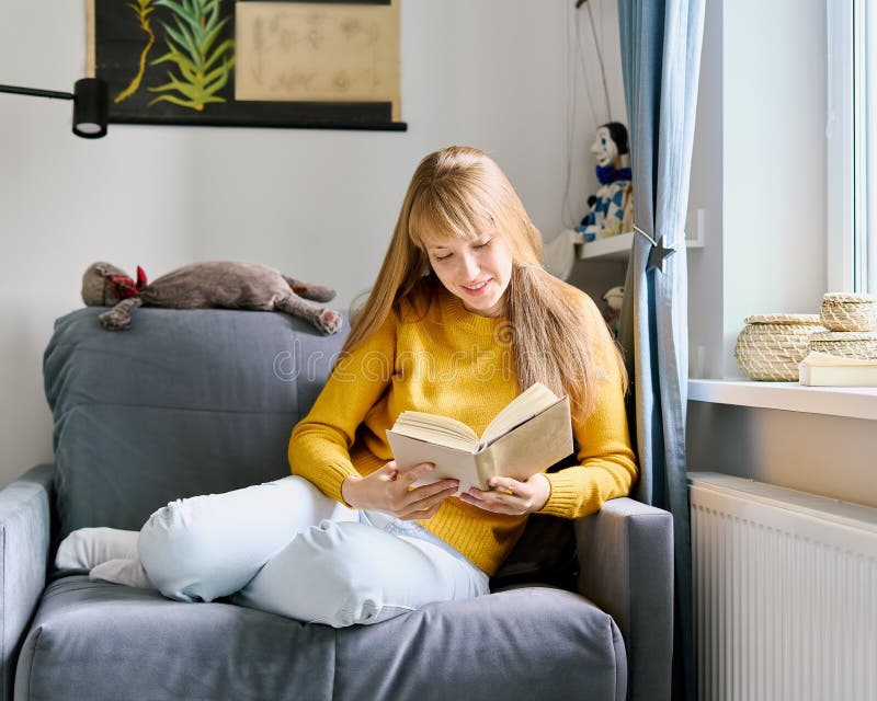 Female sitting on sofa and reading novel. Social media detox. Slow paced lifestyle. Mental wellbeing on quarantine. Smiling female enjoying literature. Calm bookworm spending day off gadgets. Female sitting on sofa and reading novel. Social media detox. Slow paced lifestyle. Mental wellbeing on quarantine. Smiling female enjoying literature. Calm bookworm spending day off gadgets