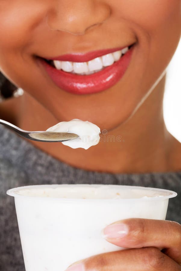 Ung kvinna som äter yoghurt som den sunda frukosten eller mellanmålet. arkivbilder Ung kvinna som äter yoghurt som den sunda frukosten eller mellanmålet. arkivbilder