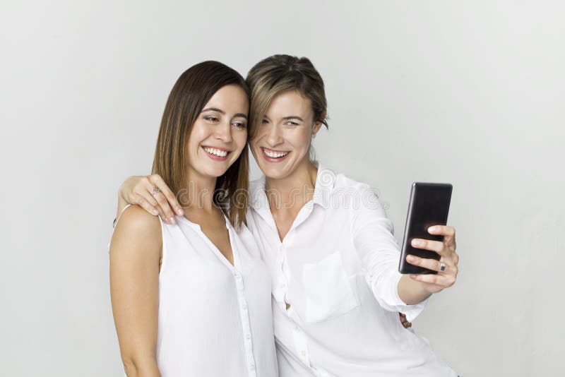 Ung kvinna två i den vita skjortan som har gyckel med danandeselfie ST arkivbild Ung kvinna två i den vita skjortan som har gyckel med danandeselfie ST arkivbild