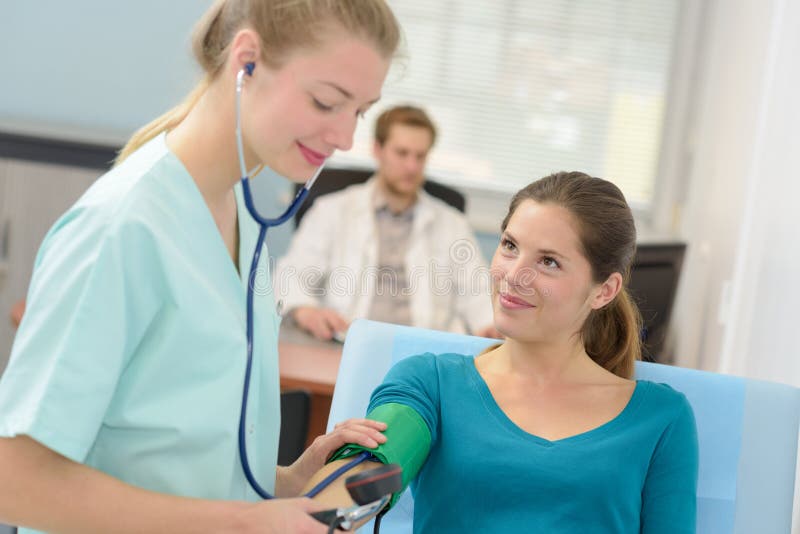 Ung kvinnlig doktor som kontrollerar blodtryckpatienten royaltyfri fotografi Ung kvinnlig doktor som kontrollerar blodtryckpatienten royaltyfri fotografi