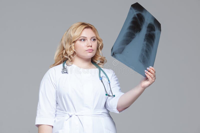 Ung kvinnlig doktor som ser r?ntgenstr?lebilden av lungor arkivbild Ung kvinnlig doktor som ser r?ntgenstr?lebilden av lungor arkivbild