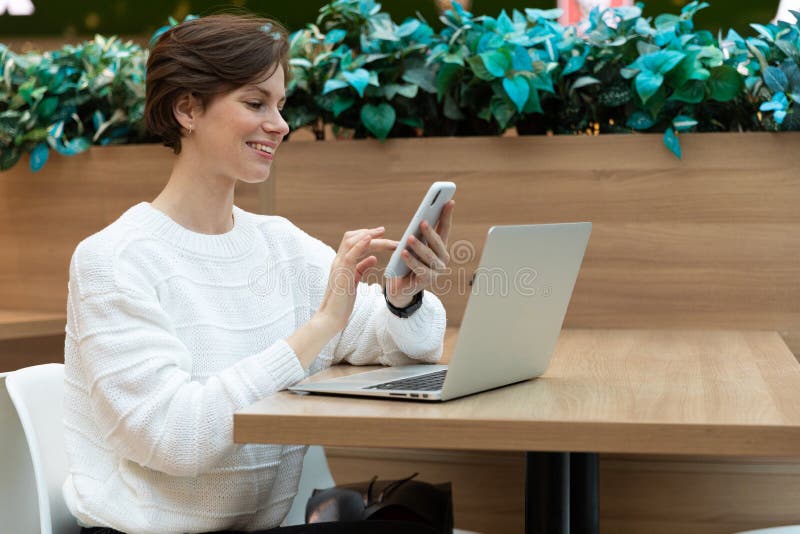 Ung kvinnlig frilansare som arbetar med en bärbar dator i ett trendkafé arkivfoto