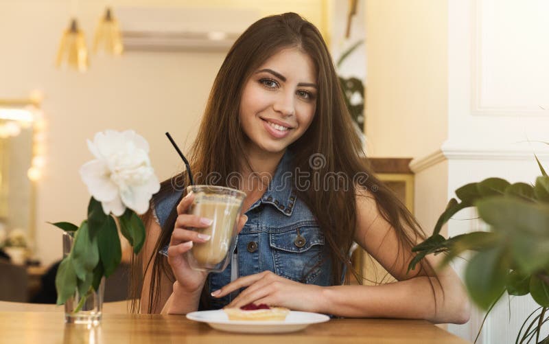 Ung le kvinna med kaffekoppen på kafét. Lycklig tillfällig flicka som dricker kaffe på kafét
