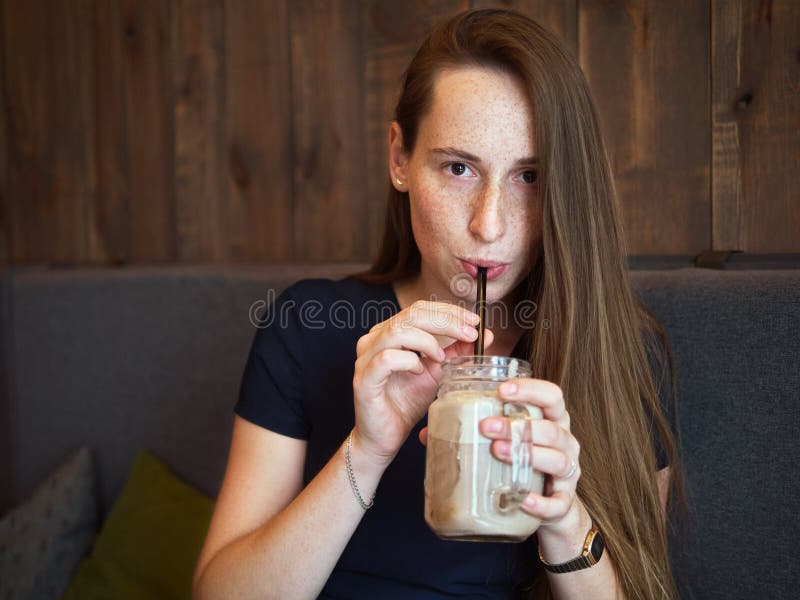 Ung lycklig härlig rödhårig mankvinna för stående med fräknar som dricker kaffe i kafé på kaffeavbrottet royaltyfria bilder Ung lycklig härlig rödhårig mankvinna för stående med fräknar som dricker kaffe i kafé på kaffeavbrottet royaltyfria bilder