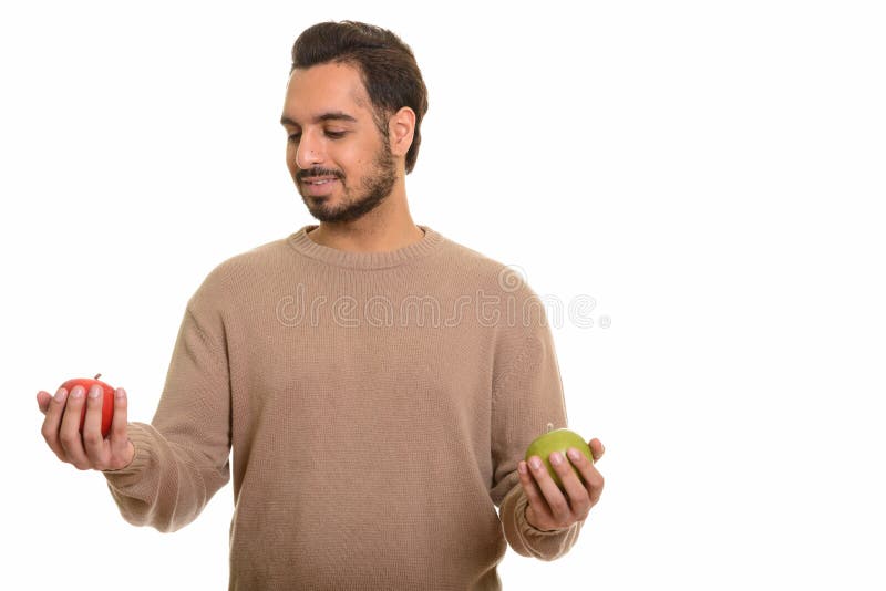 Ung lycklig indisk man som väljer mellan det röda och gröna äpplet royaltyfri fotografi Ung lycklig indisk man som väljer mellan det röda och gröna äpplet royaltyfri fotografi