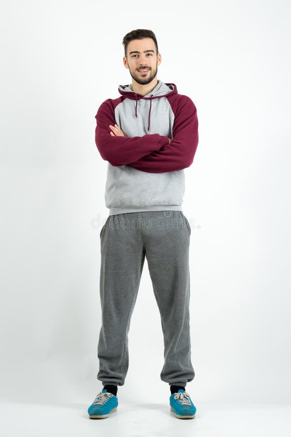 Ung lycklig skäggig tillfällig man i sportswear med korsade händer royaltyfri foto Ung lycklig skäggig tillfällig man i sportswear med korsade händer royaltyfri foto