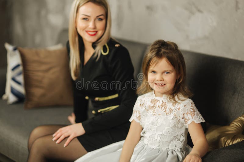 Ung mamma och liten dotter hemma som sitter på soffan Attraktiv moder i svart klänning lycklig familj royaltyfria bilder Ung mamma och liten dotter hemma som sitter på soffan Attraktiv moder i svart klänning lycklig familj royaltyfria bilder