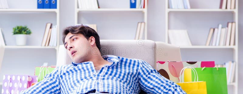 Ung man efter att ha handlat för mycket hemma. Den unge mannen efter att ha handlat för mycket hemma